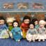Pieniä nukkekotinuken kokoisia nukkeja kauniissa mekoissaan. Nukkejen takana sinisävyinen koristeellinen pahvipakkaus. Nukkeja on 8 kappaletta.